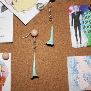 May include: A pair of light blue flower-shaped earrings with a pink bead and silver chain.