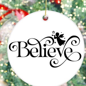 May include: White ceramic Christmas ornament with a black silhouette of an angel playing a trumpet and the word "Believe" in a decorative script.