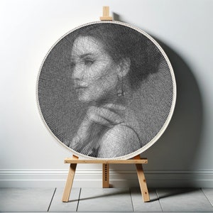 May include: A black and white portrait of a person created with string art. The art is displayed on a white circular frame and mounted on a wooden easel.