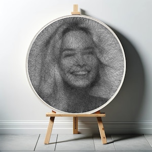 Puede incluir: Un retrato en blanco y negro de la cara de una persona creado con arte de cuerda en un lienzo circular blanco. El lienzo está montado en un caballete de madera.