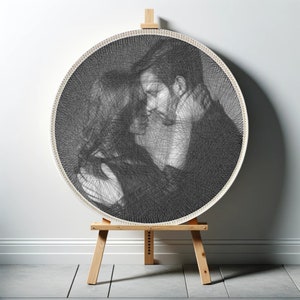 Könnte beinhalten: Ein Schwarzweiß-String-Art-Porträt von zwei Personen, die sich umarmen, auf einem Holzstaffelei ausgestellt.