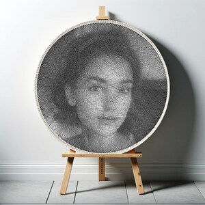 May include: A black and white portrait of a person's face created with string art on a round wooden frame. The frame is on a wooden easel.