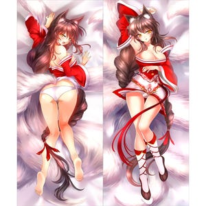 Op de afbeelding: Een bodykussen met een gestileerd anime-personage met vossenoren en een lange, bruine staart. Het personage draagt een rood-witte outfit met rode accenten. Het kussen heeft een witte achtergrond.
