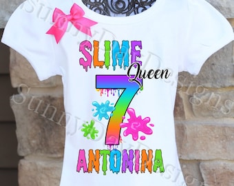 May include: White t-shirt with a rainbow slime design. The design includes the words "Slime Queen" and the number "7" with dripping slime. The name "Antonina" is written below the number.