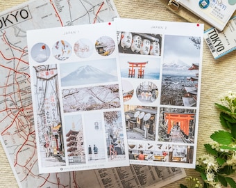 May include: Two sheets of stickers featuring images of Japan. The first sheet has images of Mount Fuji, cherry blossoms, a red pagoda, and a street scene. The second sheet has images of a red torii gate, a street scene, a mountain, and a red lantern. The text "JAPAN 1" and "JAPAN 2" is printed at the top of each sheet.