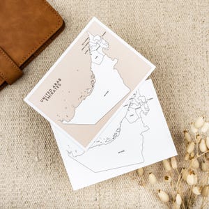 May include: Two black and white maps of the United Arab Emirates, one with a beige background and the other on a white background. The map on the beige background has the text "United Arab Emirates" printed on it.