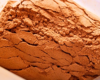 Puede incluir: Primer plano de un montón de canela molida, una especia marrón cálida con una textura rugosa.