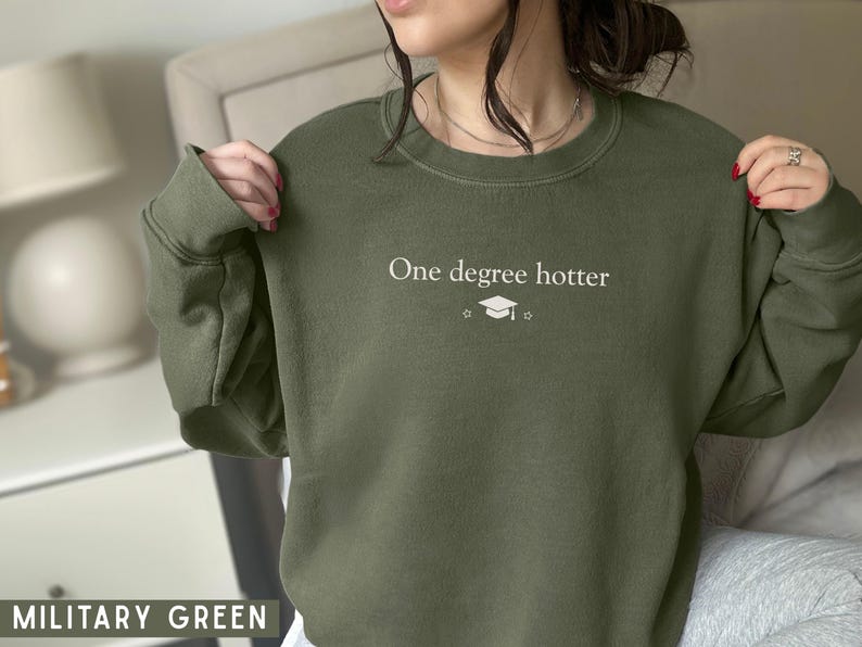 Pu&ograve; includere: Felpa verde militare con la scritta "One degree hotter" e una grafica del cappello di laurea. Il top a girocollo a maniche lunghe &egrave; realizzato in materiale morbido.