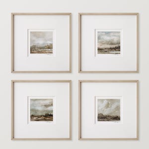 Op de afbeelding: Vier ingelijste landschapskunstprints. Elke print toont een gedempt kleurenpalet van beige, bruin en grijs, dat een bewolkte lucht boven een landschap afbeeldt. De prints zijn geplaatst in licht houten frames met witte passe-partouts, waardoor een samenhangende set ontstaat.