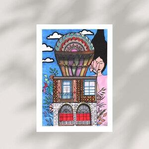 Peut inclure: Illustration artistique d'un b&acirc;timent surmont&eacute; d'une montgolfi&egrave;re, sur fond de ciel bleu avec des nuages. Le b&acirc;timent a des fen&ecirc;tres cintr&eacute;es avec des portes rouges et des motifs floraux. Une personne tient une fleur rose.