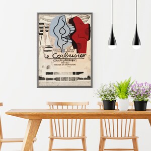 May include: A framed poster with a black and white image of a building and a red and blue abstract design. The poster is titled "Le Corbusier" and includes the text "oeuvre plastique 1903-1937" and "TABLEAUX ET ARCHITECTURE".