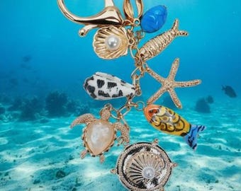 Adorno para bolso/llavero con peces, conchas marinas y estrellas de mar de porcelana.