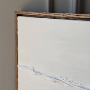 K&ouml;nnte beinhalten: Ein wei&szlig;es Leinwandbild mit einem Holzrahmen. Das Bild hat eine strukturierte Oberfl&auml;che mit subtilen Linien und Pinselstrichen.
