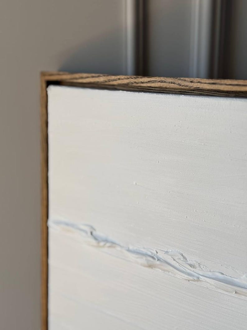 K&ouml;nnte beinhalten: Ein wei&szlig;es Leinwandbild mit einem Holzrahmen. Das Bild hat eine strukturierte Oberfl&auml;che mit subtilen Linien und Pinselstrichen.