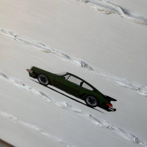 K&ouml;nnte beinhalten: Ein gr&uuml;nes Auto, das auf einem wei&szlig;en, strukturierten Hintergrund gemalt ist.