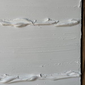 K&ouml;nnte beinhalten: Wei&szlig;e strukturierte Farbe auf einer Leinwand mit einem Holzrahmen.