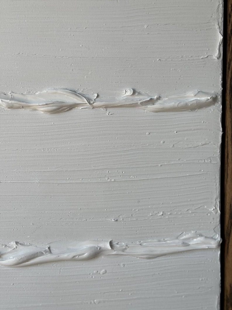 K&ouml;nnte beinhalten: Wei&szlig;e strukturierte Farbe auf einer Leinwand mit einem Holzrahmen.