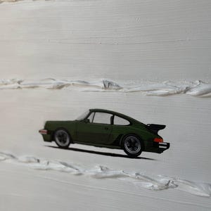 K&ouml;nnte beinhalten: Ein gr&uuml;ner Porsche 911 Sportwagen, der auf einem wei&szlig;en, strukturierten Hintergrund gemalt ist.