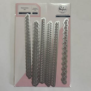 May include: A package of six silver metal crafting dies with decorative edge designs. The package includes the text "Stand-alone Die" and "Fancy Edge". The dies are from Pinkfresh Studio, designed in the USA.