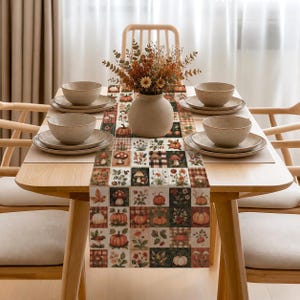 May include: A rectangular table runner featuring a grid pattern of autumn-themed illustrations including pumpkins, mushrooms, and wildflowers in shades of orange, brown, and green, centered on a wooden table with four place settings and a vase.