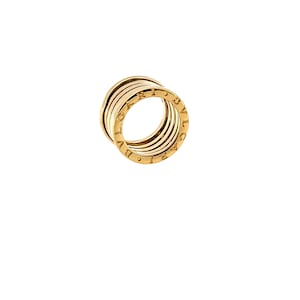 May include: A gold ring featuring a multi-layered, coiled design with a cylindrical profile. The outer edge of the band is engraved with the text BVLGARI in capital letters, showcasing a polished metallic finish and a structured, architectural form.