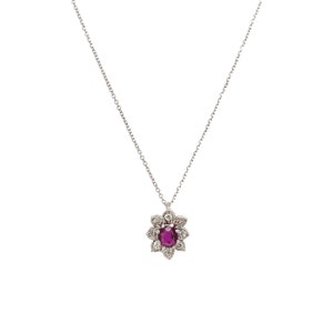 Puede incluir: Un collar de cadena de plata con un colgante que presenta una piedra preciosa de rubí rodeada por un halo de diamantes más pequeños.