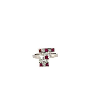 May include: A silver ring with a geometric design. The ring features a letter "T" shape, with alternating red and clear square-cut stones. The ring is set against a white background.