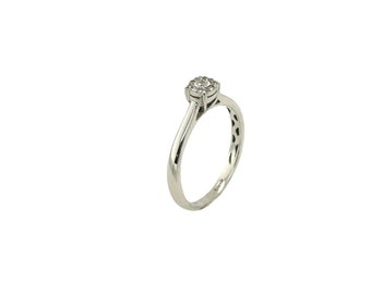 Puede incluir: Un anillo de plata con un grupo de pequeños diamantes redondos en el centro. La banda es lisa y se estrecha hacia la parte posterior, con un diseño delicado en los lados. El anillo está sobre un fondo blanco.