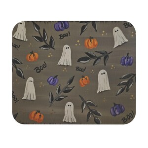 May include: A Halloween-themed decorative mat featuring a repeating pattern of white ghosts, orange pumpkins, and purple pumpkins. Black leaves and the word "Boo!" are also included in the design. The background is a muted gray.