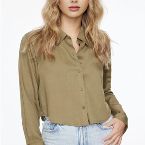 May include: A green, long-sleeved, collared shirt with a button-up front. The shirt has a cropped hem and cuffed sleeves.