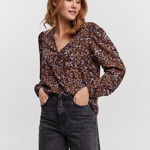 May include: A long-sleeved blouse with a floral print in shades of brown, purple and yellow. The blouse has a V-neckline and a relaxed fit.