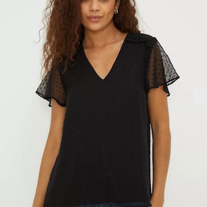 May include: Black polka dot top with sheer, ruffled sleeves and a v-neck.