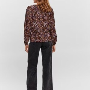 May include: A long-sleeved blouse with a floral print in shades of purple, brown, and white. The blouse has a V-neckline and a relaxed fit.