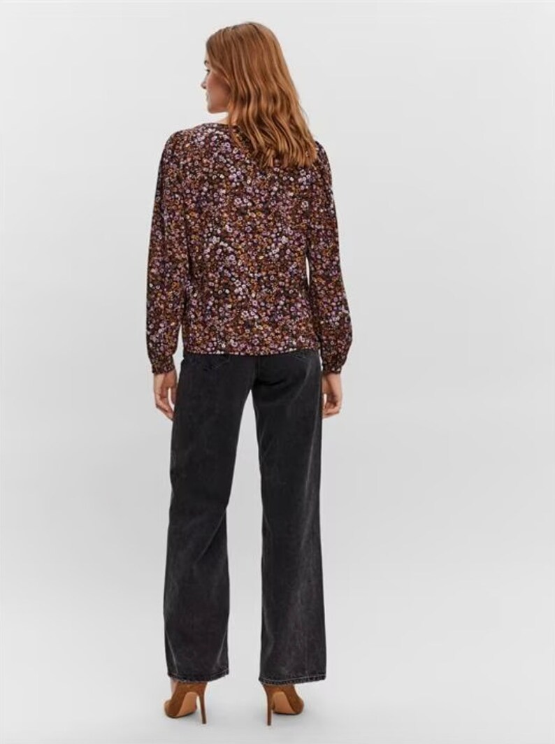 May include: A long-sleeved blouse with a floral print in shades of purple, brown, and white. The blouse has a V-neckline and a relaxed fit.