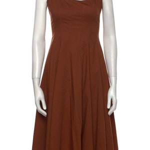 Puede incluir: Un vestido midi sin mangas de color marr&oacute;n con escote cuadrado y falda fluida.