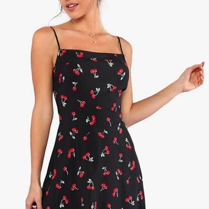 May include: A black sleeveless mini dress with a cherry print. The dress has a square neckline and thin straps.