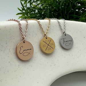 Könnte beinhalten: Drei Halsketten aus Gold, Silber und Roségold mit runden Anhängern. Die Anhänger zeigen ein Fischsymbol und einen personalisierten Text, darunter die Namen "Emma", "Thomas" und das Datum "20.04.24".