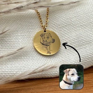 Könnte beinhalten: Goldkette mit einem runden Anhänger, der ein schwarz-weißes, graviertes Bild eines Hundekopfes zeigt. Der Anhänger ist mit dem Namen "Nelly" beschriftet.