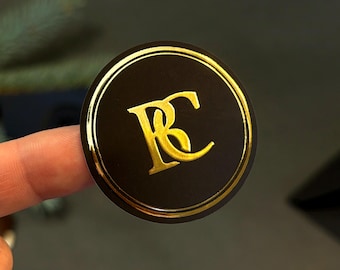 Può includere: Un adesivo rotondo nero con un bordo dorato e le lettere "RC" in oro.
