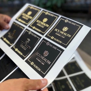May include: A sheet of black and gold stickers with the text "The Hive" and "ECU Health" with the date "October 17, 2023".