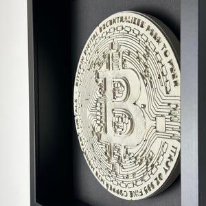 Peut inclure: Une pièce de monnaie Bitcoin en 3D imprimée en blanc, encadrée, avec le texte "Bitcoin Digital Decentralized Peer to Peer" et "Trust No One, Free Copper Wire" autour du bord.