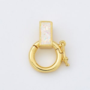 May include: Gold-toned clasp with a white iridescent rectangular piece. The clasp is a circle with a small hook on the side.
