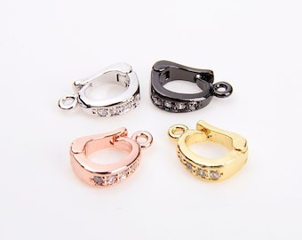 May include: Four different colored metal clasps with clear crystal accents. The clasps are silver, rose gold, black, and gold.