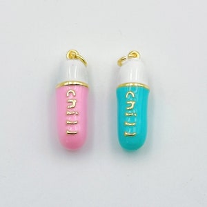 May include: Two gold pill charms, one pink and one turquoise blue, with the word "chill" written in gold lettering.