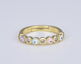 Puede incluir: Anillo de oro con una fila de amuletos de ojo turco de colores. Cada amuleto tiene un centro blanco y un anillo exterior azul, rosa o morado.