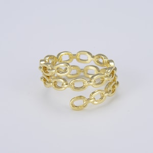 May include: A gold-toned ring with a chain link design. The ring is made of multiple chain links that are twisted together to form a spiral shape.