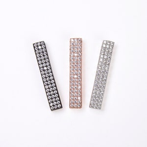 May include: Three rectangular hair clips with a row of clear rhinestones on each side. The clips are black, rose gold, and silver.