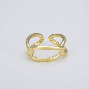 May include: A gold-toned ring with a simple, modern design. The ring is made of two intertwined bands that form a figure eight shape.