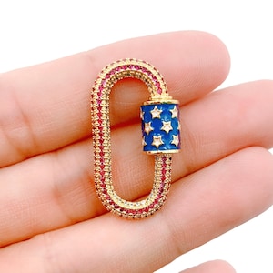 May include: Gold-toned charm with a red and blue enamel design. The charm is shaped like a lobster claw and features a blue enamel section with white stars.