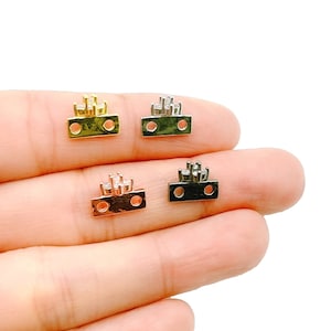 May include: Four small metal charms with a crown design and clear rhinestones. The charms are in gold, silver, rose gold, and black.